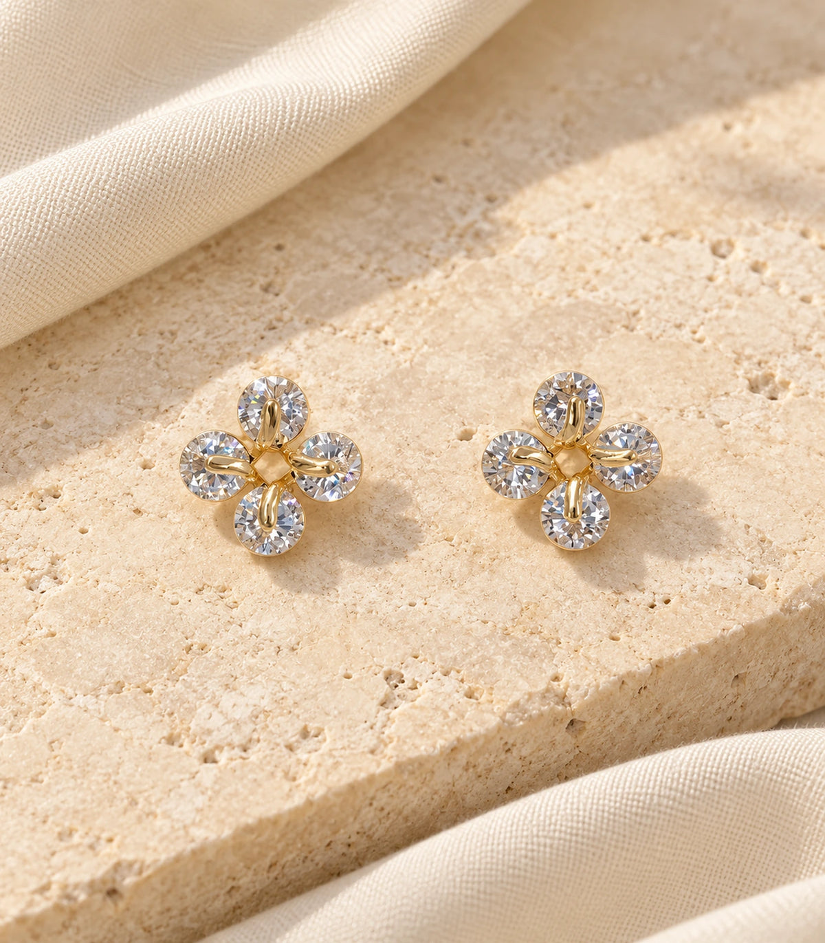 JIMIKI gold tone crystal flower stud earrings, matching pair on textured stone #color_gold-tone