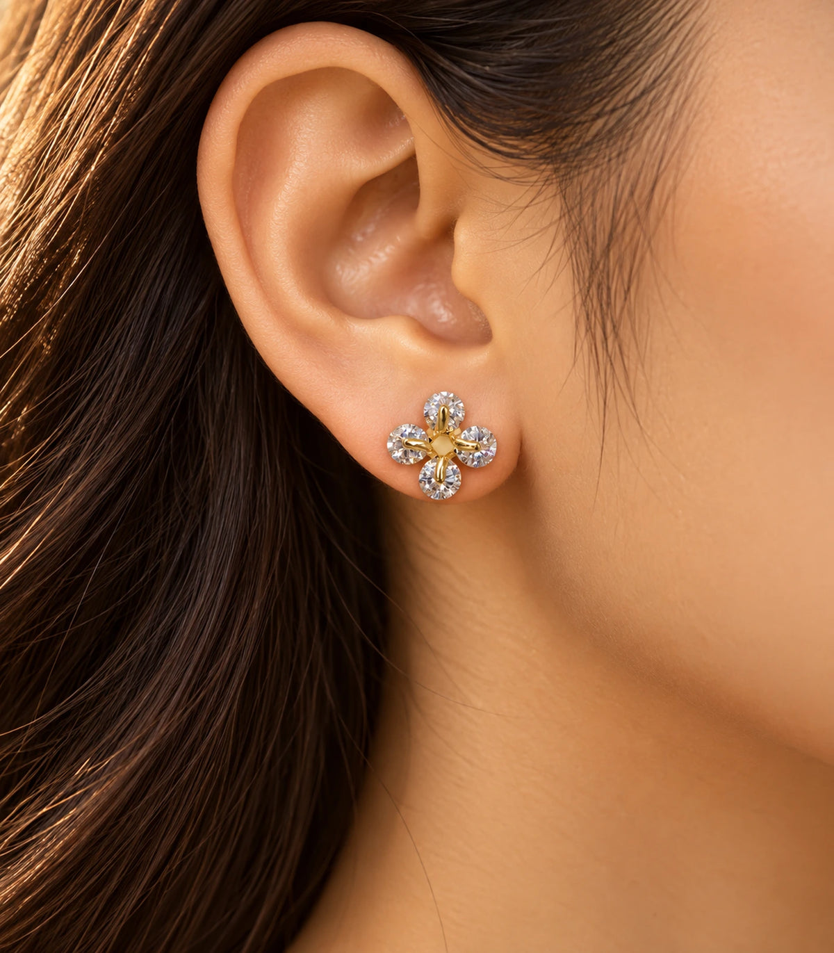 JIMIKI gold tone crystal flower stud earrings, shown worn in warm editorial lighting #color_gold-tone