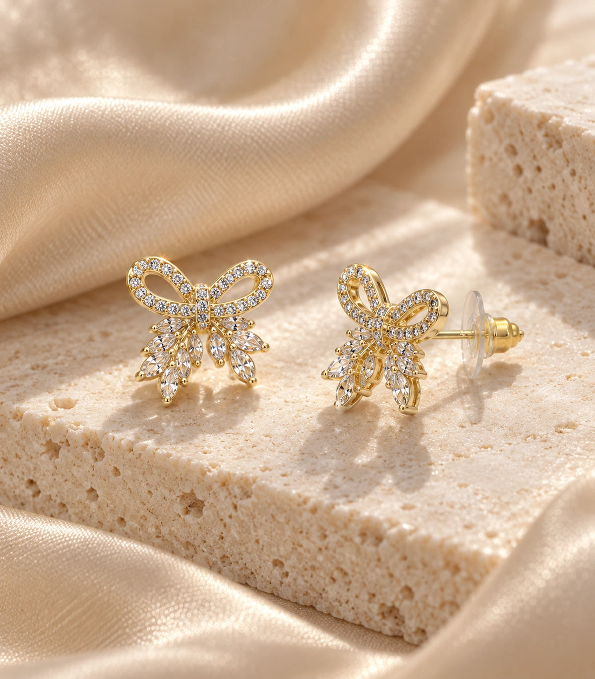 JIMIKI Gold-Tone Crystal Loop Bow Stud Earrings in Gold / Clear, editorial flat lay