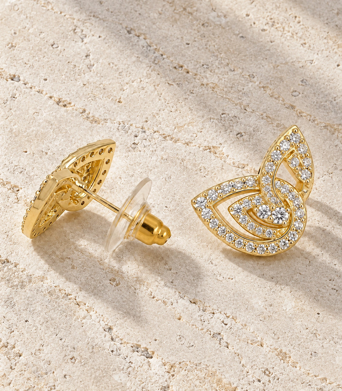 JIMIKI Crystal Open Swirl Stud Earring Pair in Gold tone, editorial flat lay #color_gold tone