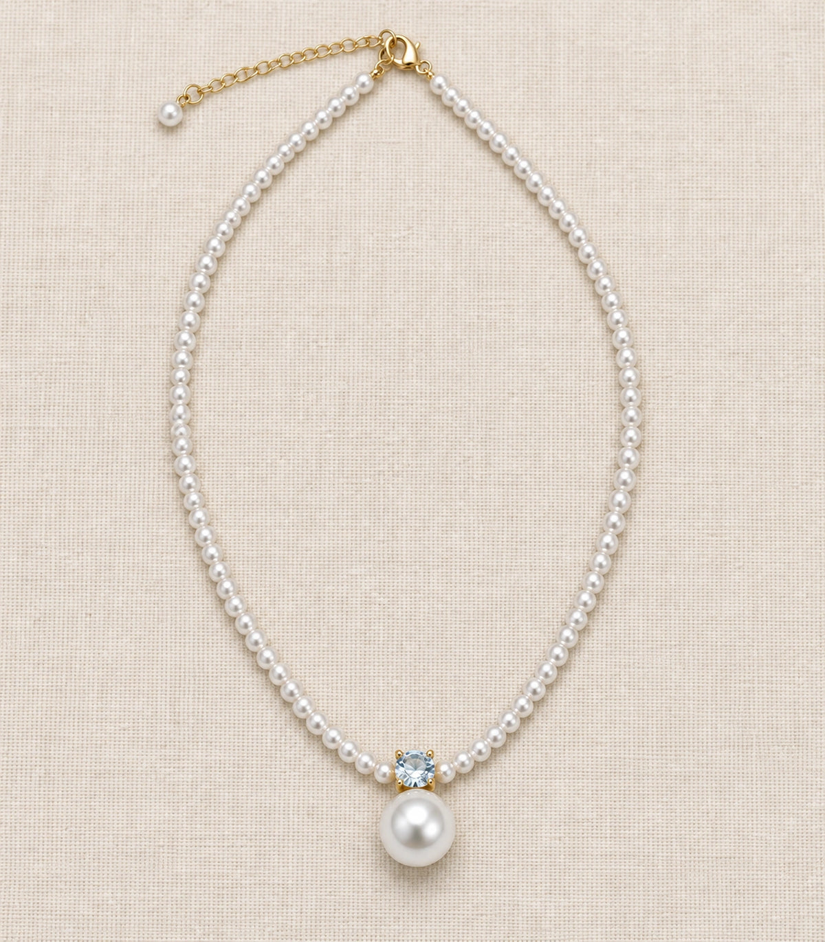 JIMIKI Gold Tone Crystal Pearl Drop Beaded Necklace in Gold tone / white, editorial flat lay