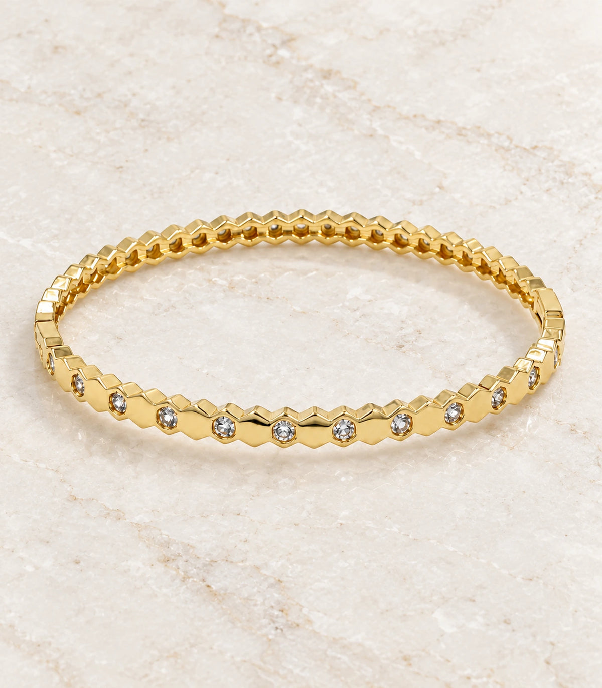 JIMIKI Gold-Tone Faceted Bezel Crystal Bangle — bangle in a styled flat lay #color_gold-tone / clear