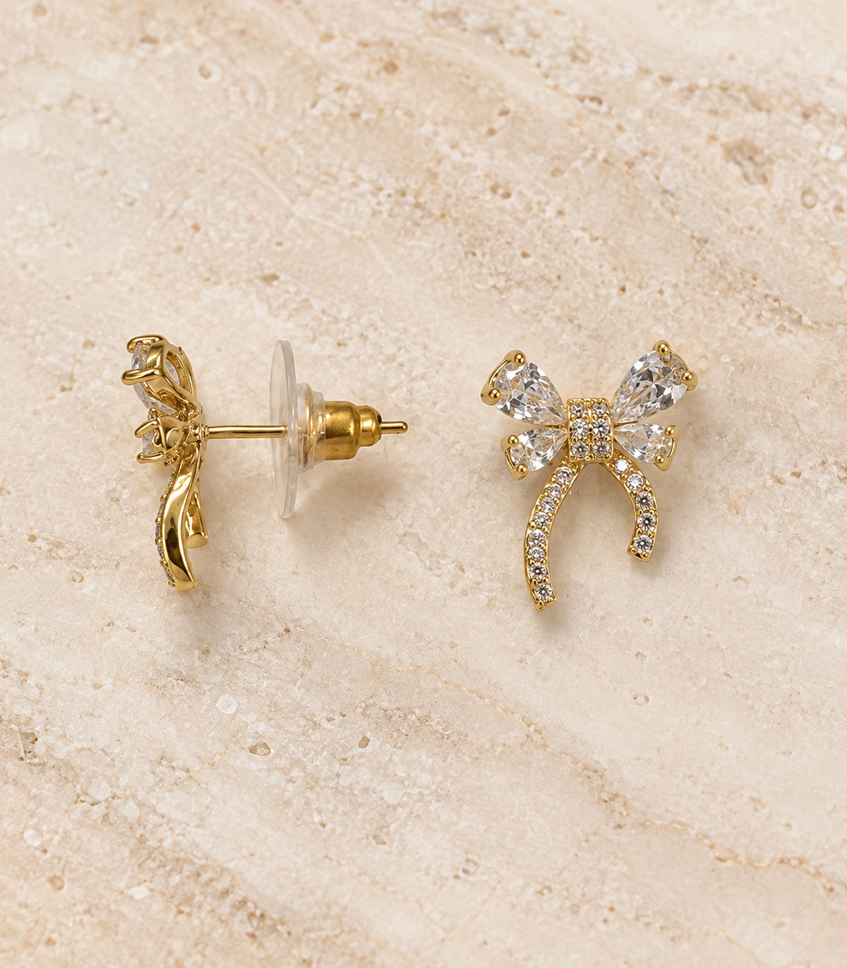 JIMIKI Four Pear Crystal Bow Stud Earring Pair in Gold Tone, editorial flat lay #color_gold tone