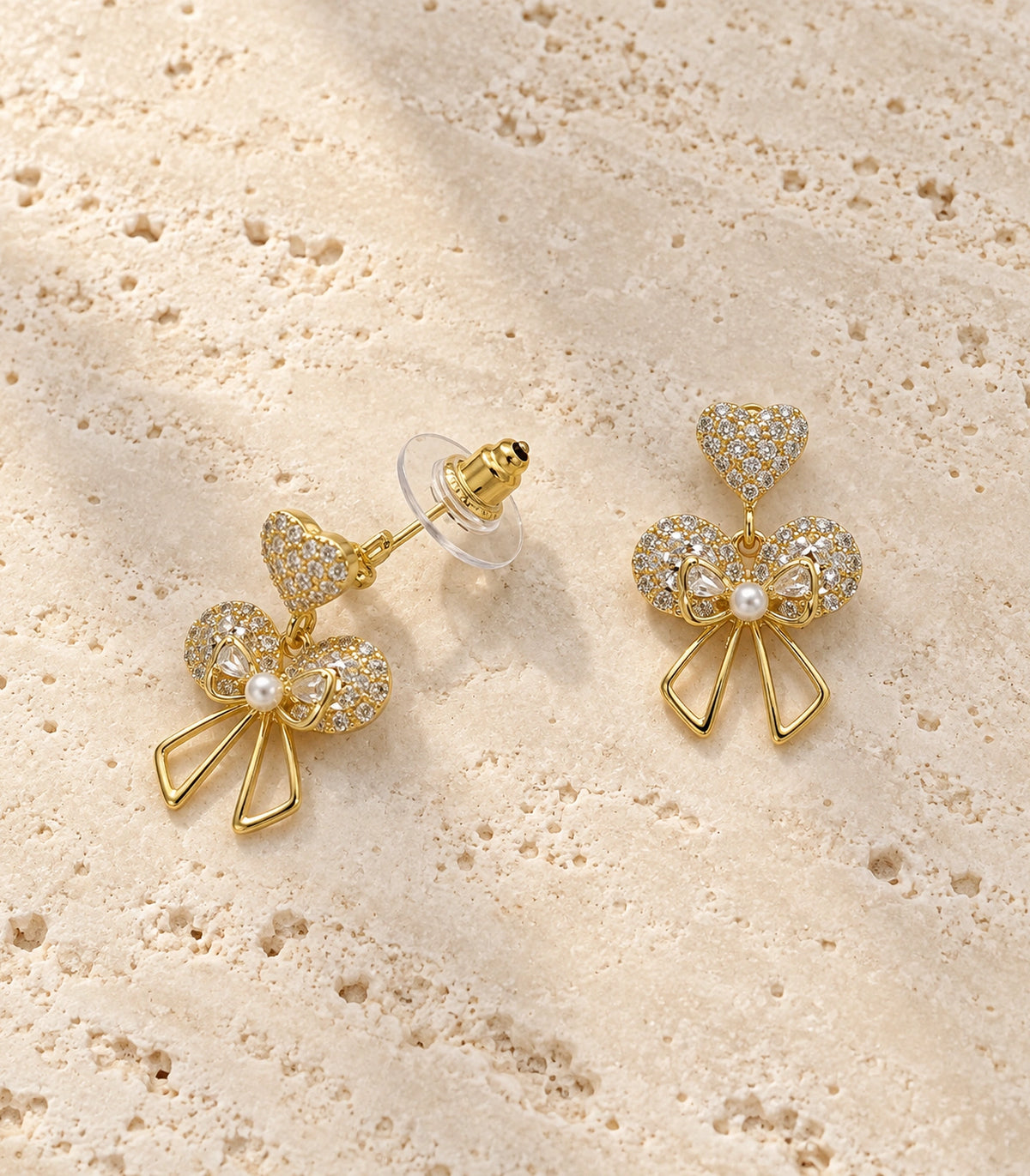 JIMIKI Gold-Tone Heart Bow Pearl Drop Earrings in Gold / Clear / White, editorial flat lay