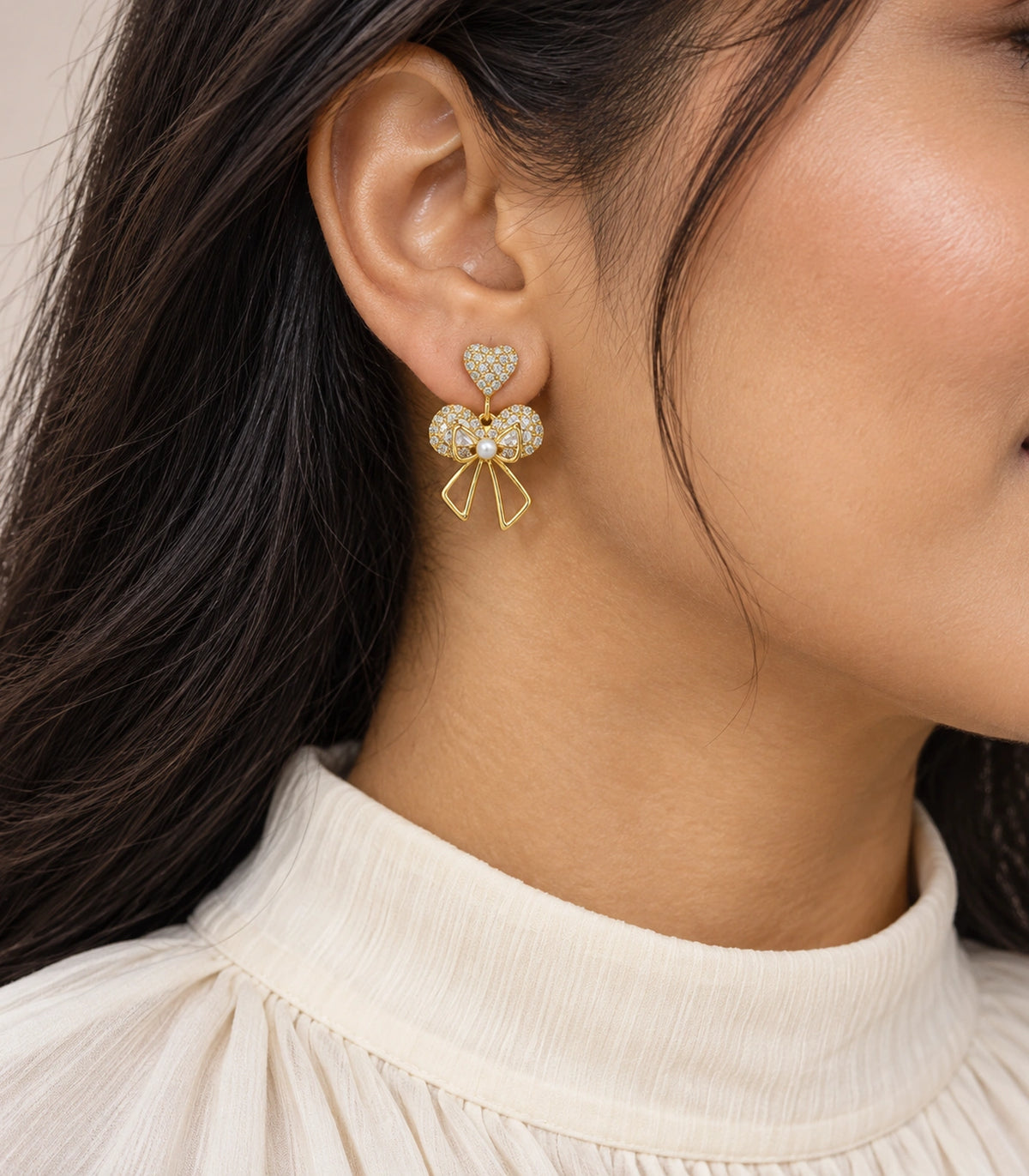 JIMIKI Gold-Tone Heart Bow Pearl Drop Earrings in Gold / Clear / White, model wearing view