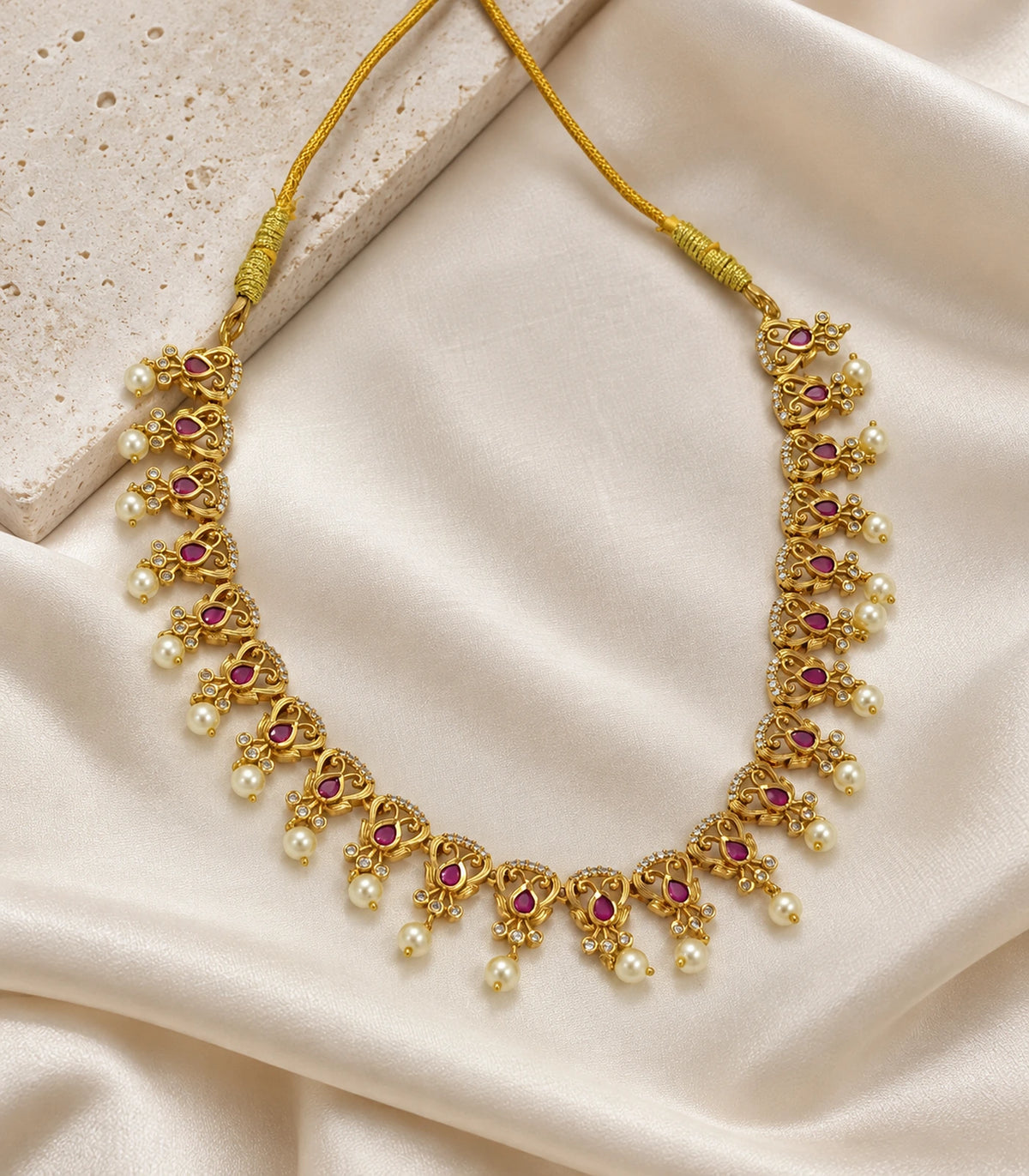 Gold Tone Magenta Pearl Leaf Collar Necklace arranged on ivory fabric