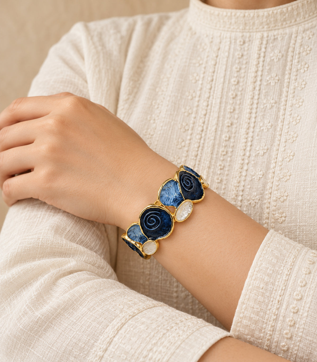 Gold-tone navy spiral and blue fan panel bracelet — editorial model view