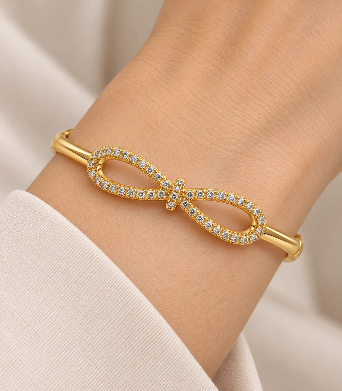 JIMIKI Gold-Tone Open Infinity Pavé Bangle — close-up of the bangle worn on the wrist #color_gold-tone / clear