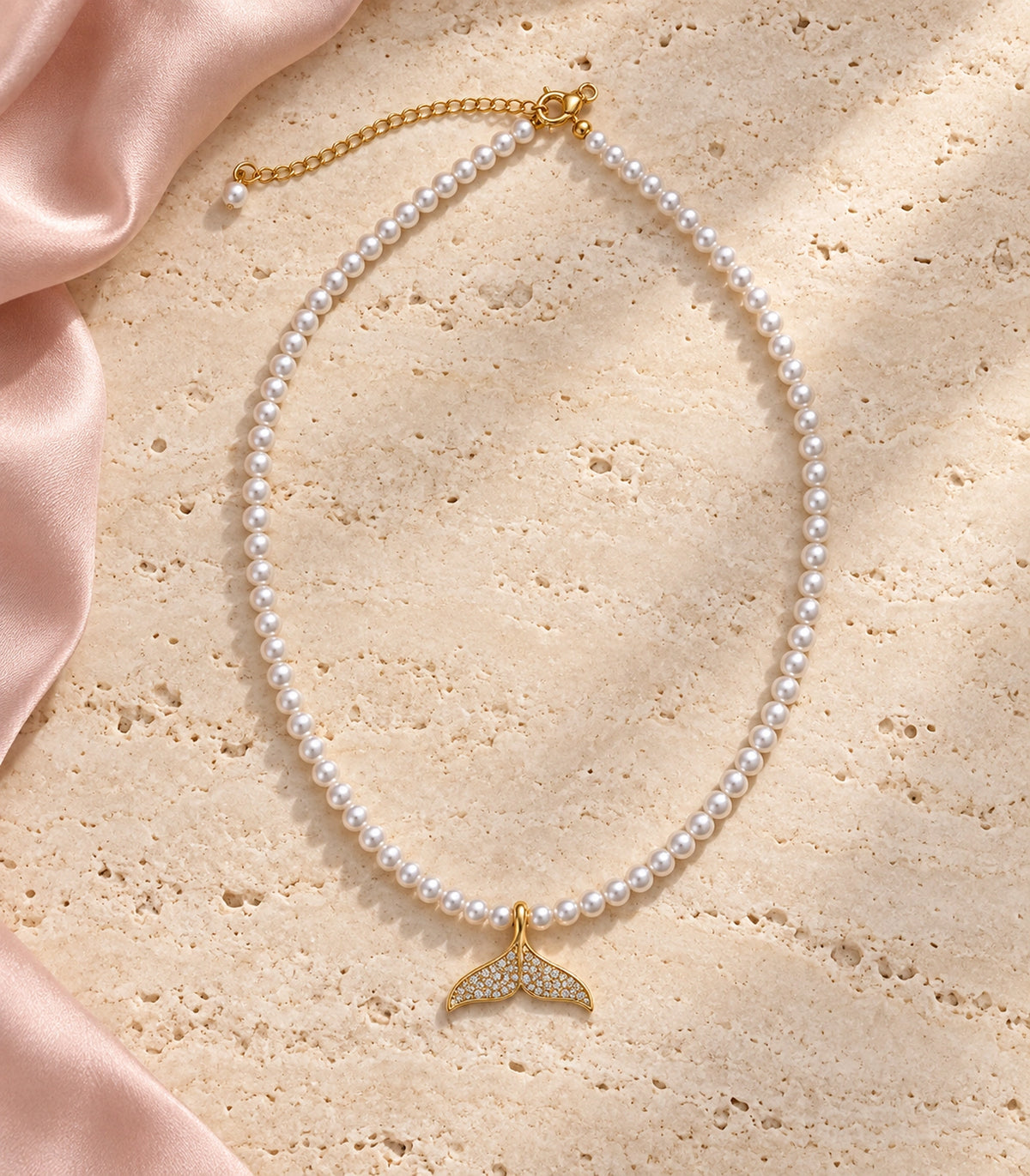 JIMIKI Pavé Whale Tail Pearl Necklace in Gold-tone, arranged in an editorial flat lay #color_gold-tone