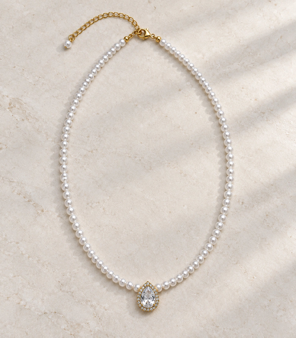 JIMIKI Gold Tone Pear Halo Crystal Pearl Style Necklace in Gold tone / white, editorial flat lay