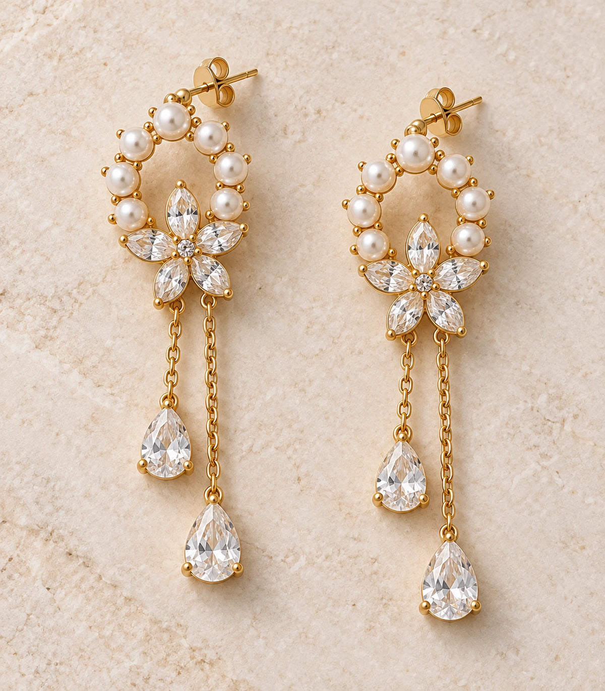 JIMIKI Gold-Tone Pearl Halo Flower Chain Drop Earrings — pair in a styled flat lay #color_gold-tone / white