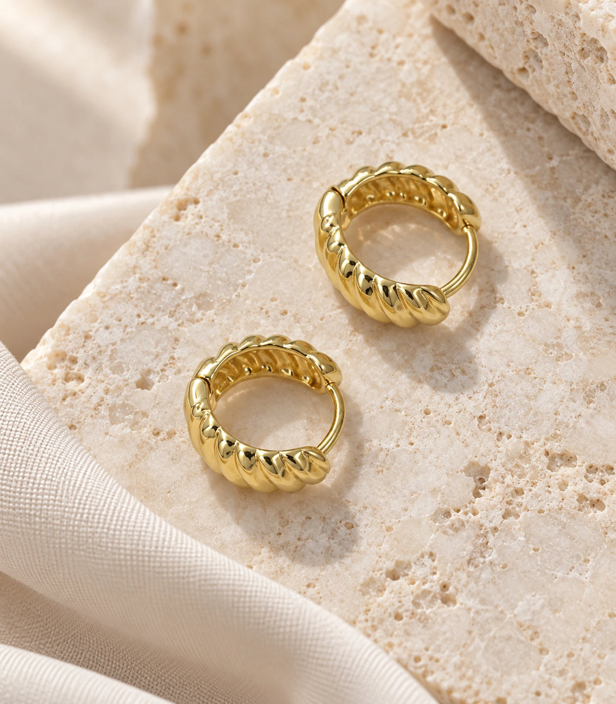 JIMIKI Gold Tone Ribbed Hoop Earrings in Gold Tone - editorial flatlay #color_gold-tone