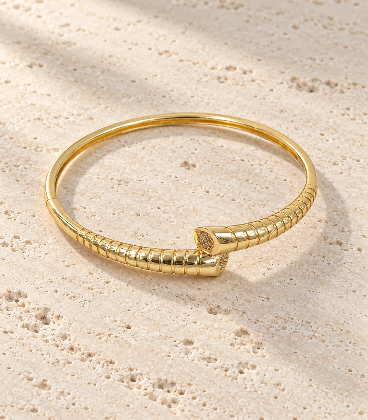 JIMIKI Gold-Tone Ribbed Pavé Tip Open Cuff Bangle — bangle in a styled flat lay #color_gold-tone / clear