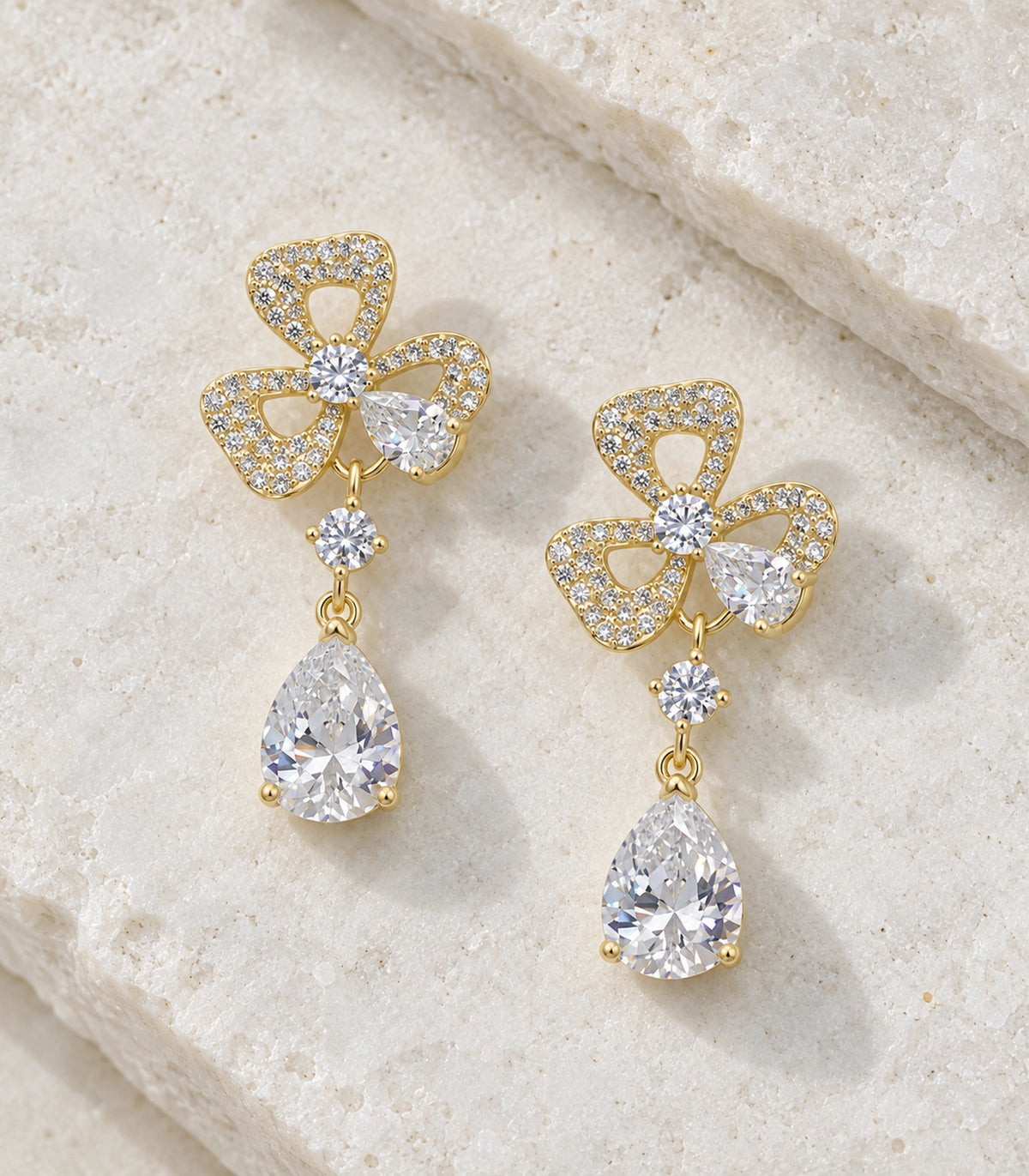 JIMIKI Gold-Tone Three-Loop Crystal Flower Pear Drop Earrings in Gold Tone, editorial flat lay