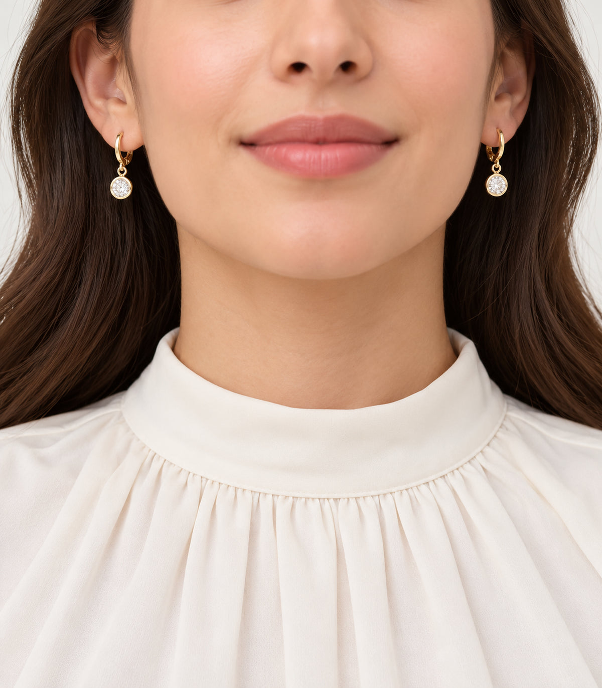 Gold-tone clear crystal hoop earrings from the three-pair set worn in a single-ear portrait