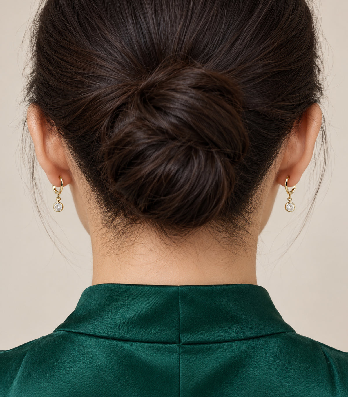 Gold tone round clear crystal hoop earrings worn in a rear view