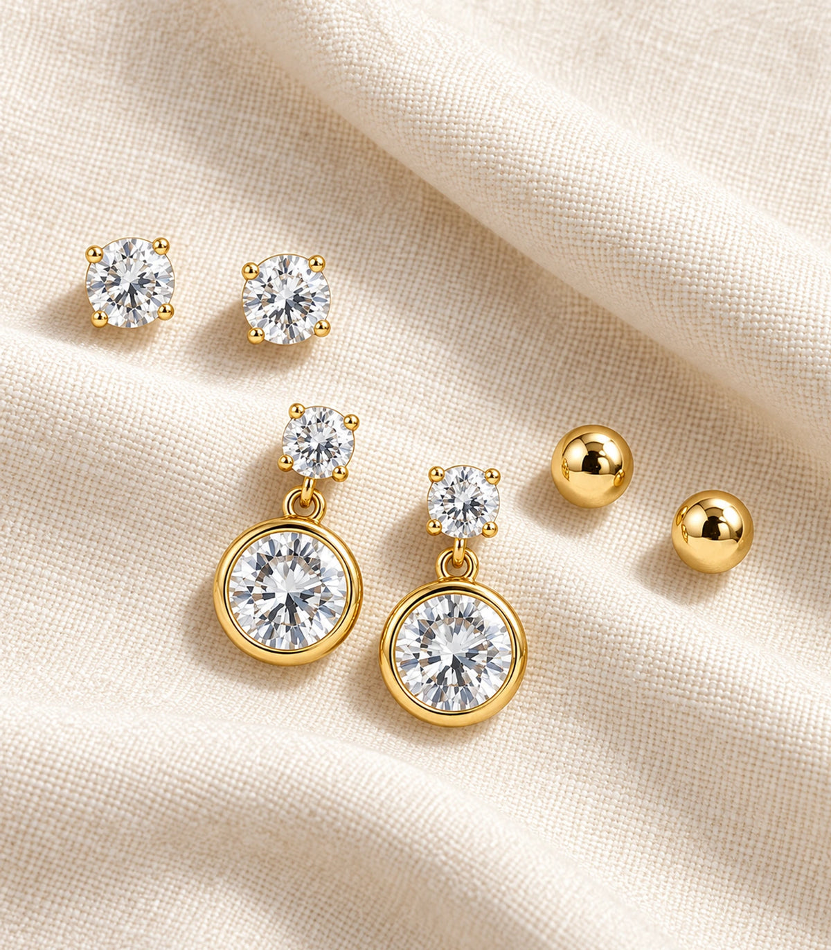 All six earrings in the gold-tone three-pair set arranged on fabric