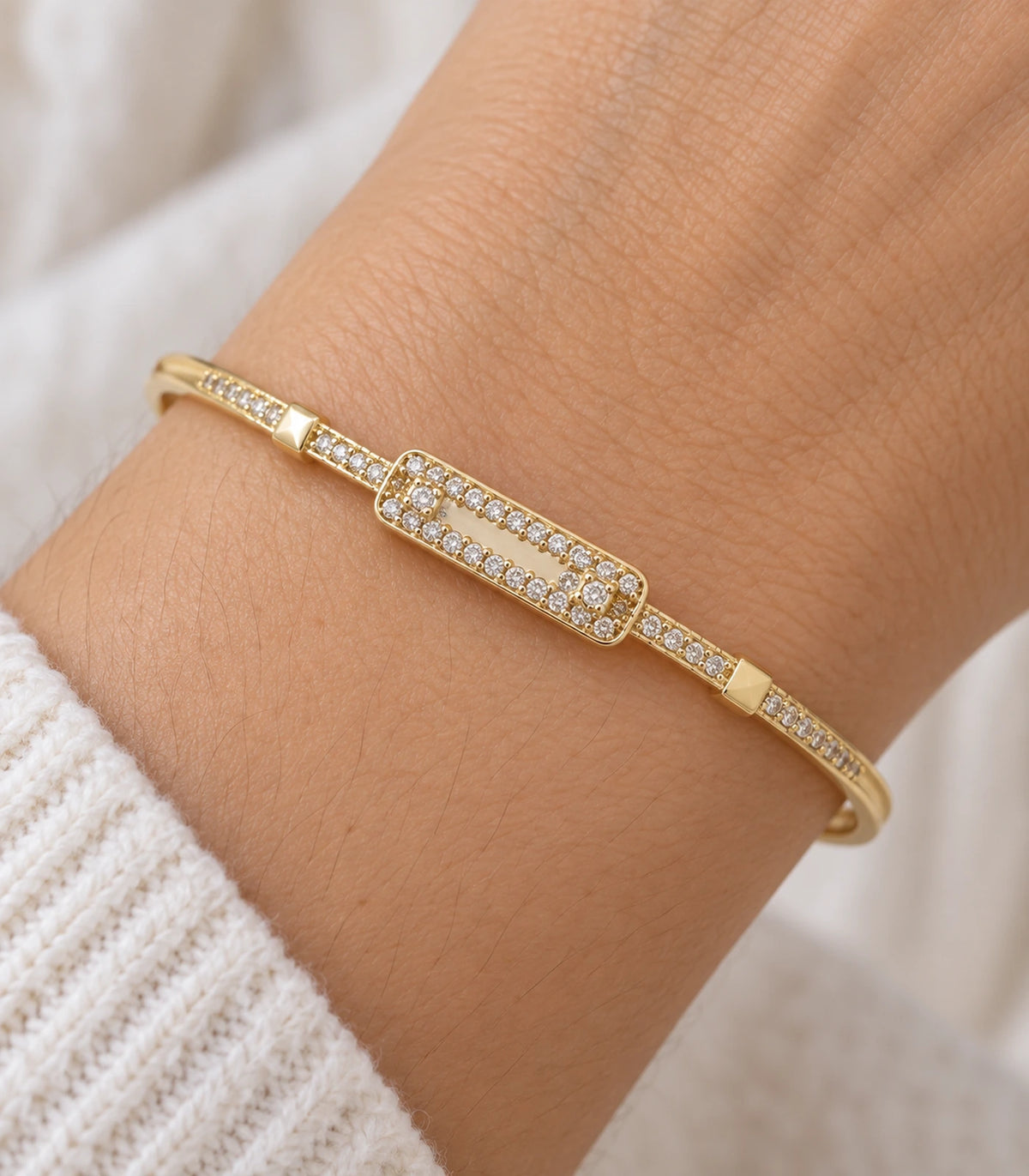 JIMIKI Gold-Tone Three Stone Open Rectangle Bangle — close-up of the bangle worn on the wrist #color_gold-tone / clear