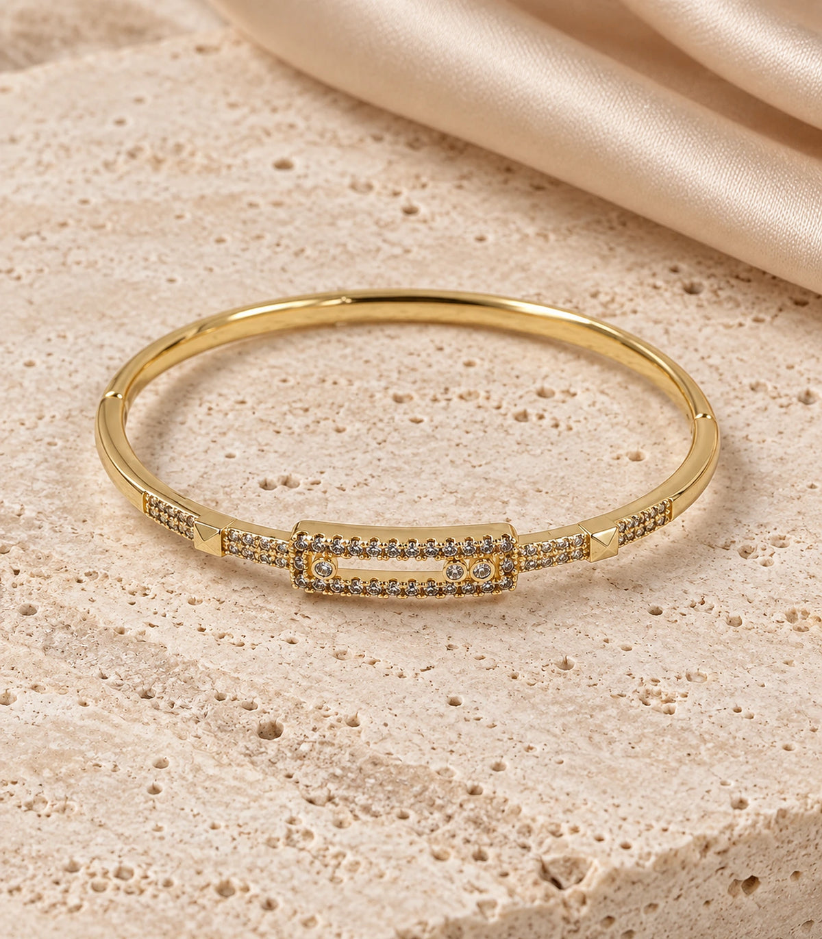 JIMIKI Gold-Tone Three Stone Open Rectangle Bangle — bangle in a styled flat lay #color_gold-tone / clear