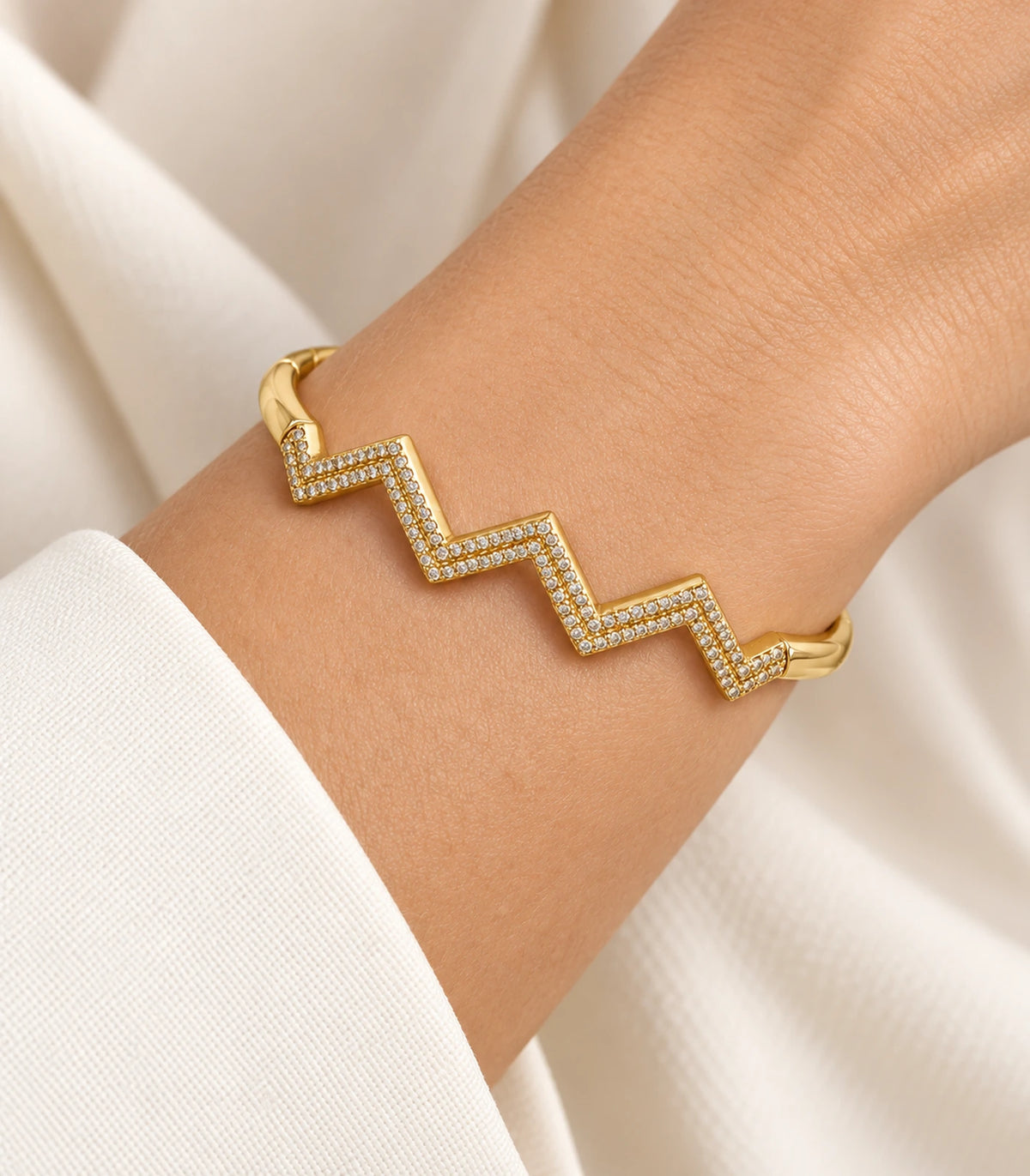 JIMIKI Gold-Tone Triple Chevron Pavé Bangle — close-up of the bangle worn on the wrist #color_gold-tone / clear