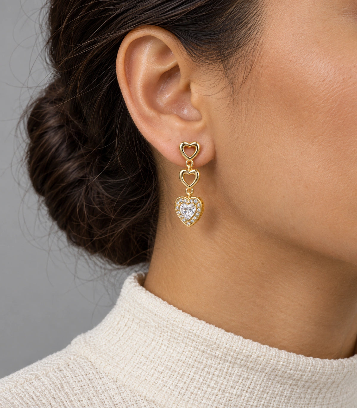 JIMIKI Triple Heart Crystal Drop Earring Pair in Gold tone / clear, model wearing view #color_gold tone / clear