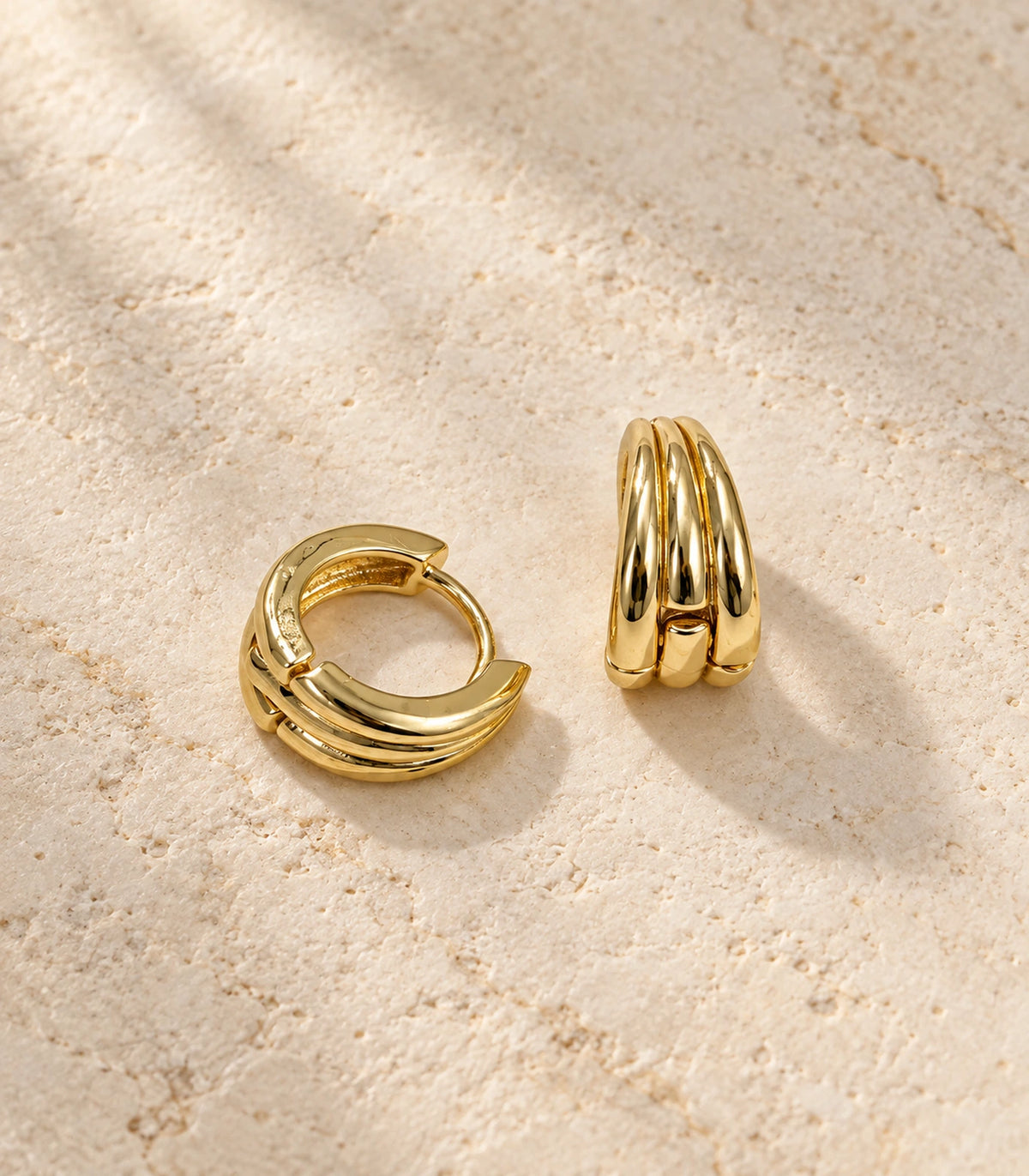 JIMIKI Triple-Ridge Huggie Hoop Earrings in Gold Tone - editorial-flatlay #color_gold-tone