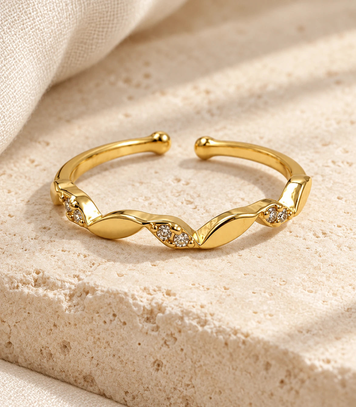 JIMIKI Gold Tone Twisted Leaf Crystal Adjustable Ring in Gold Tone - editorial flatlay #color_gold-tone