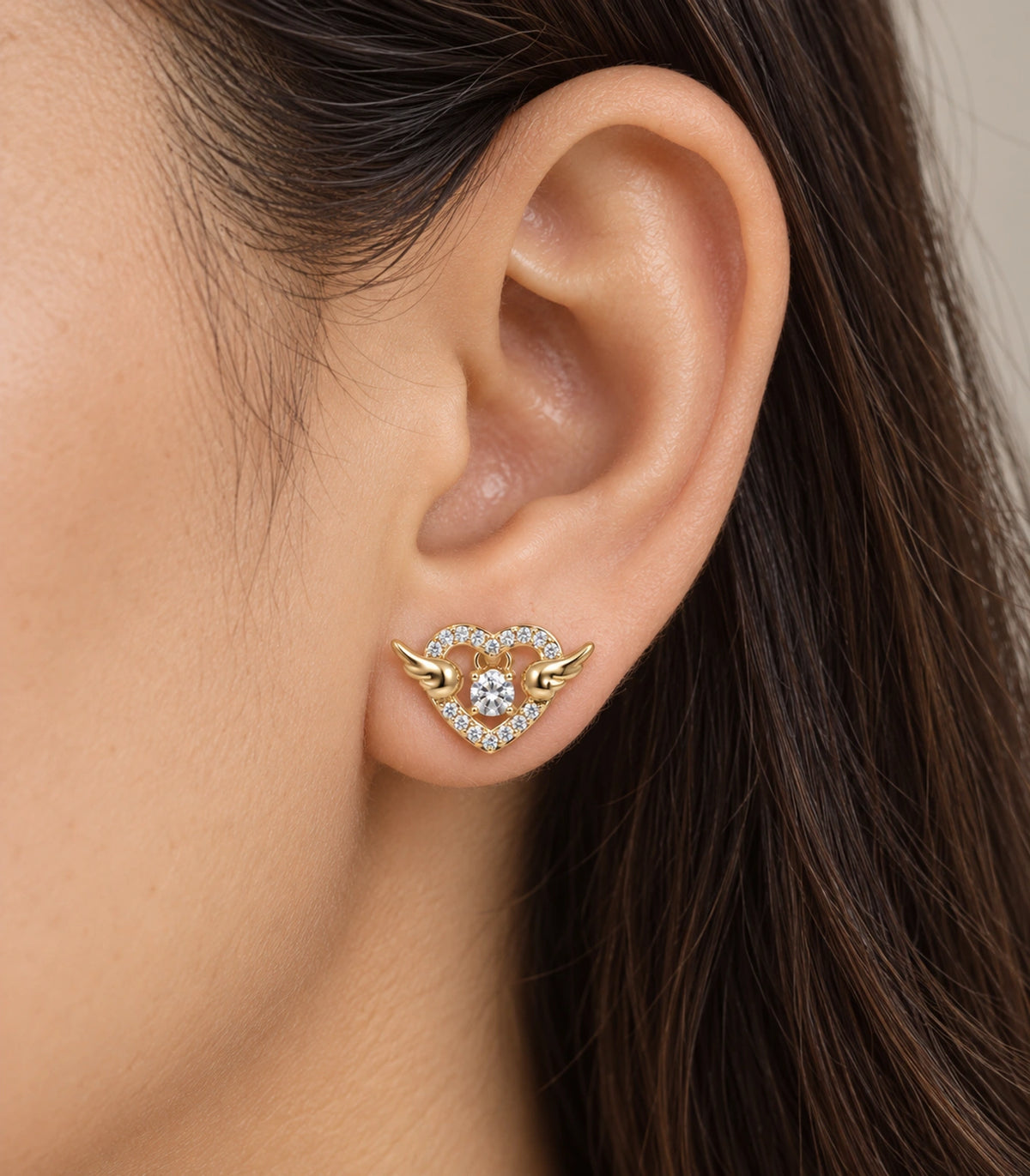 JIMIKI Winged Heart Crystal Stud Earrings in Gold Tone — worn close-up detail #color_gold-tone