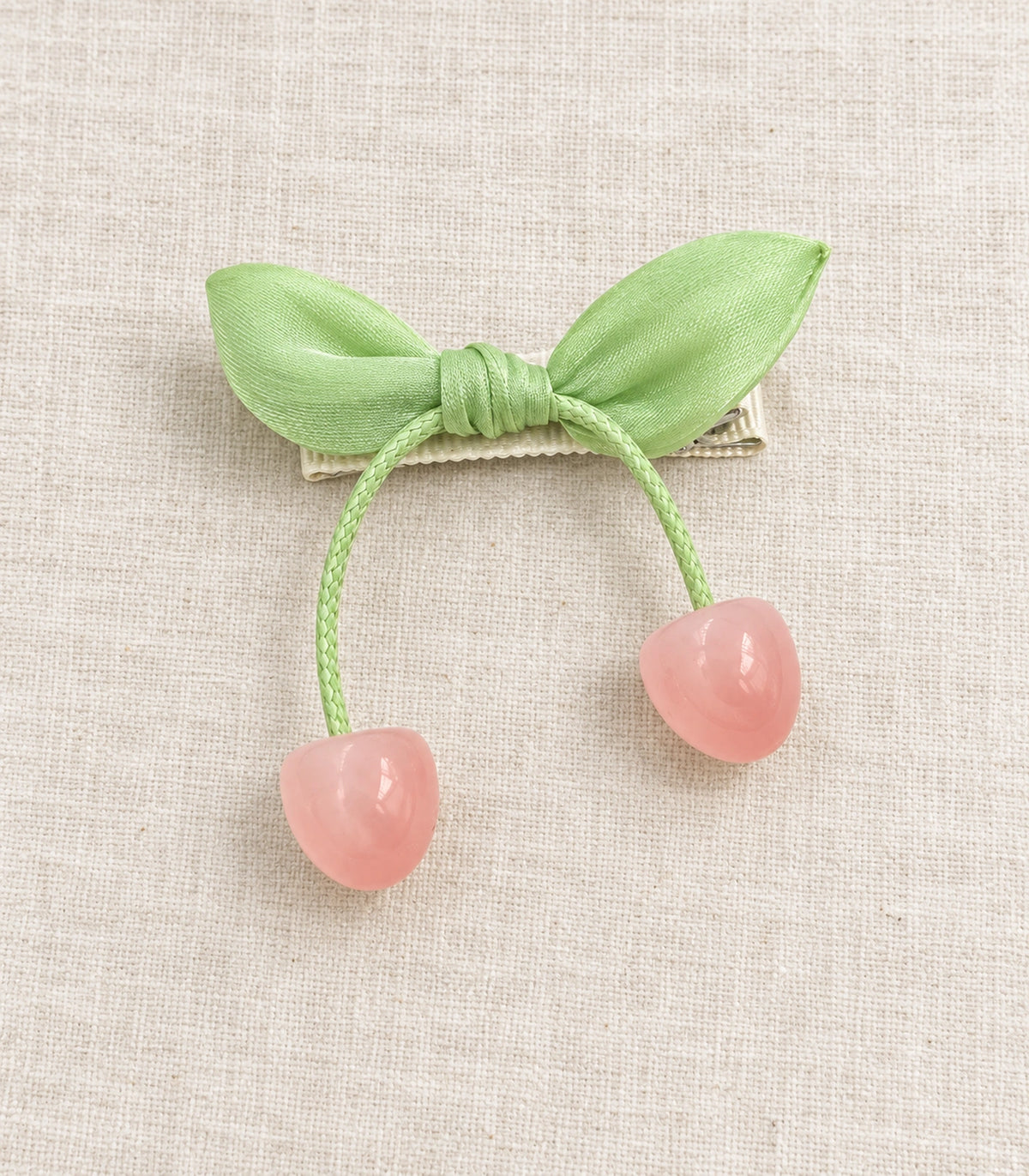 JIMIKI Green Leaf Bow Hair Clip with Cherry Charms in Green, editorial flat lay