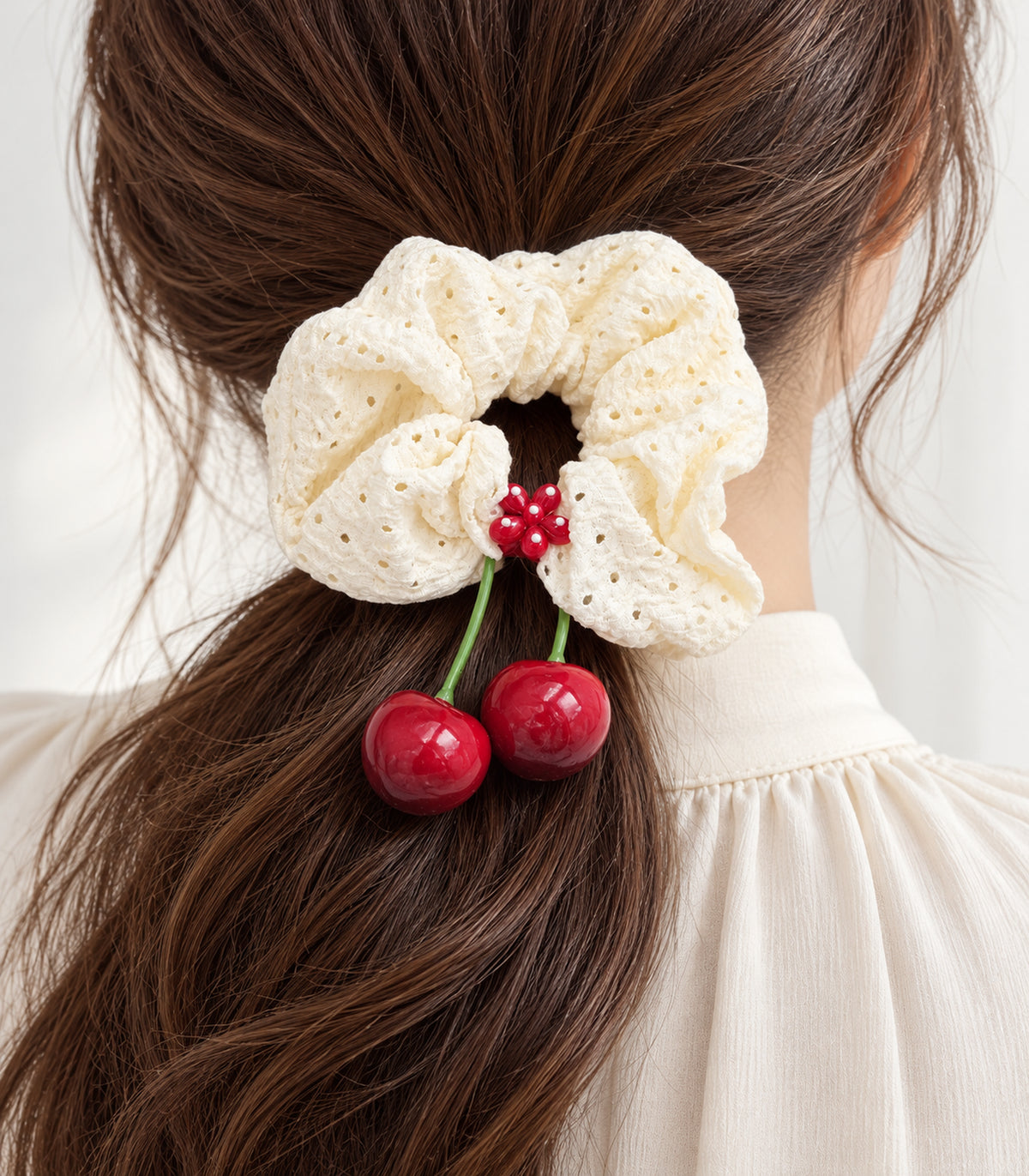 Ivory eyelet cherry scrunchie with dotted red flower centre — closeup view