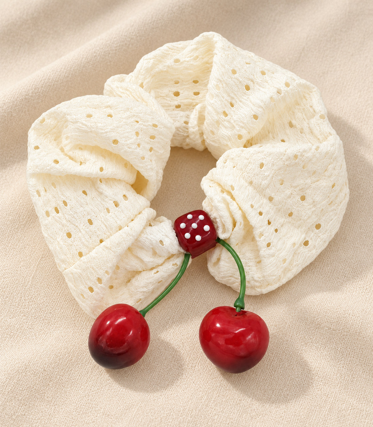 Ivory eyelet cherry scrunchie with dotted square centre, editorial flatlay