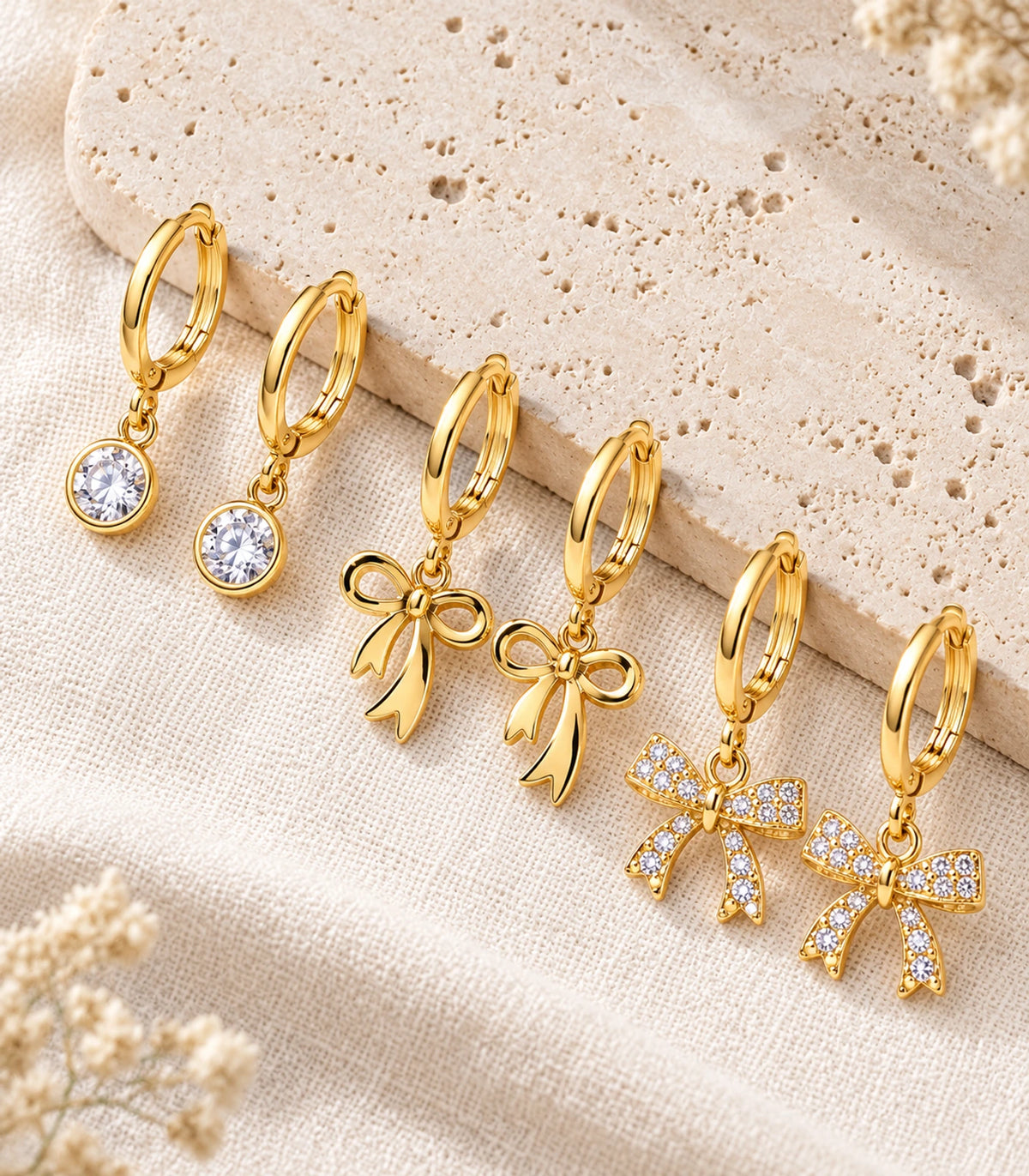 All six gold tone earrings arranged together: clear round crystal drops, polished bows and crystal-covered bows.