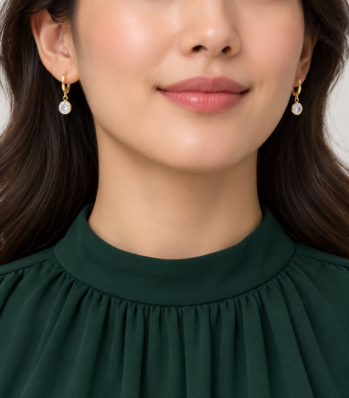 Round clear crystal drop hoops from the gold tone set, styled with a green high-neck garment.