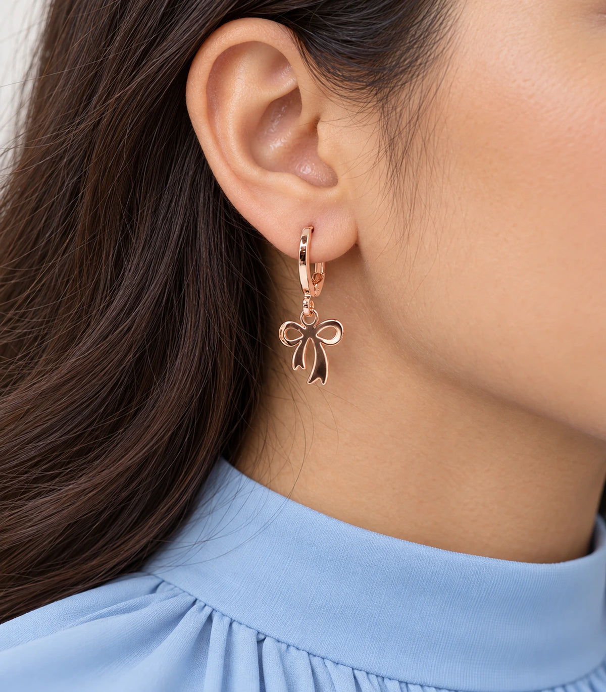 Close view of an included smooth ribbon bow hoop earring in rose gold tone