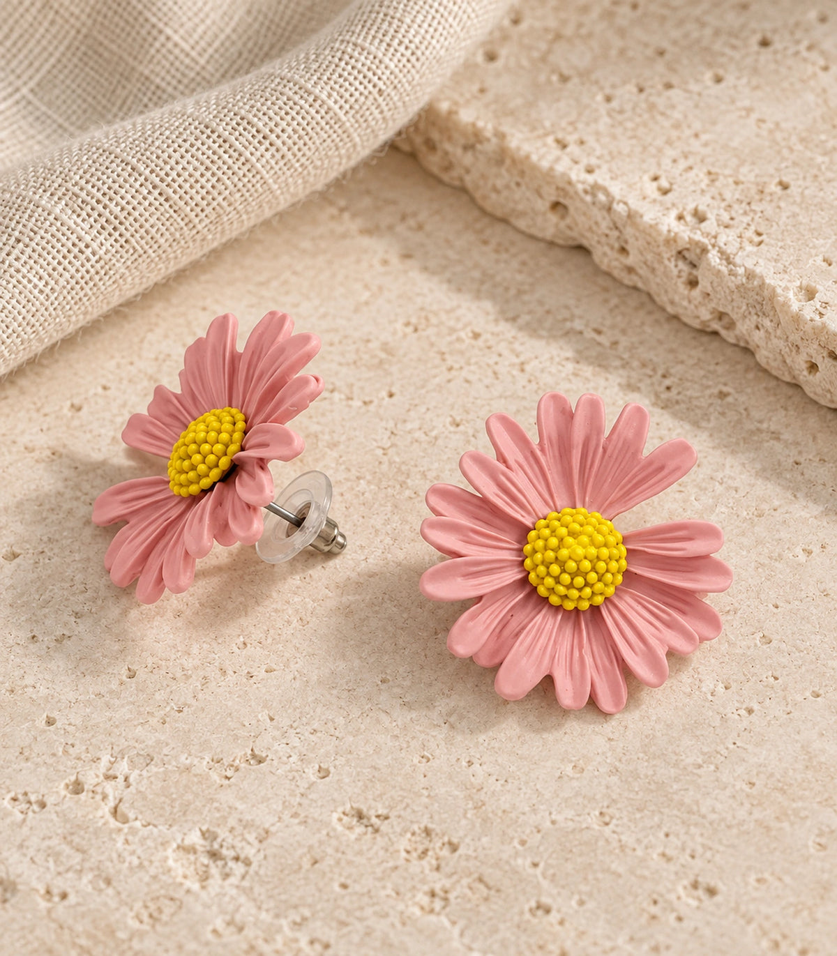 JIMIKI Light Pink yellow centre daisy stud earrings, matching pair on a styled stone surface #color_light pink