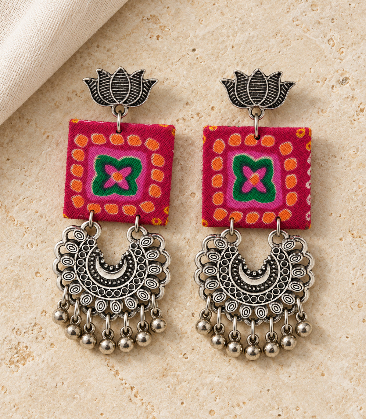 Magenta and green lotus crescent fabric earrings - editorial flatlay view