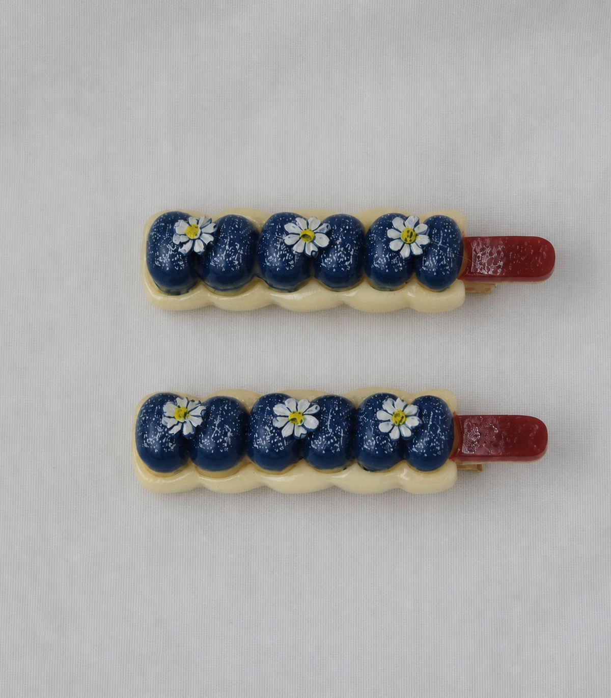 Navy Blueberry Daisy Garland Clip Pair in an editorial flat lay