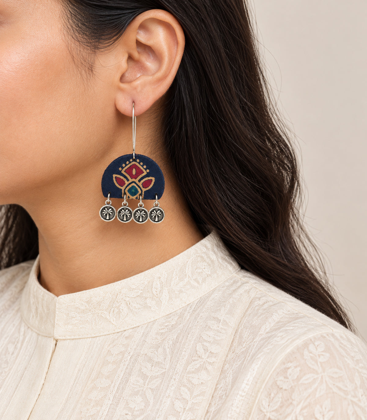 Single navy floral four-coin earring worn from a long kidney wire