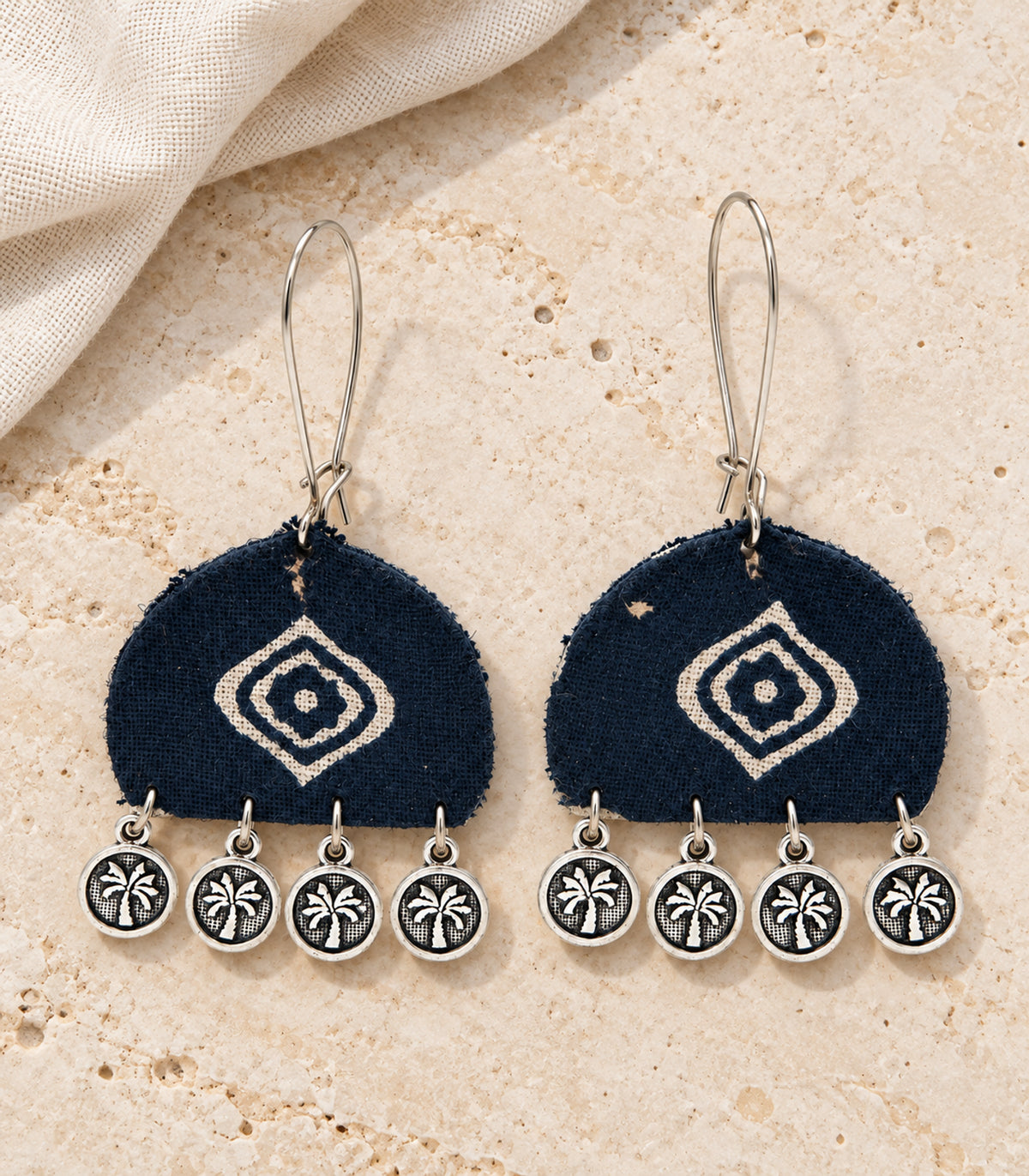 Navy and ivory diamond motif coin earrings — editorial flatlay view