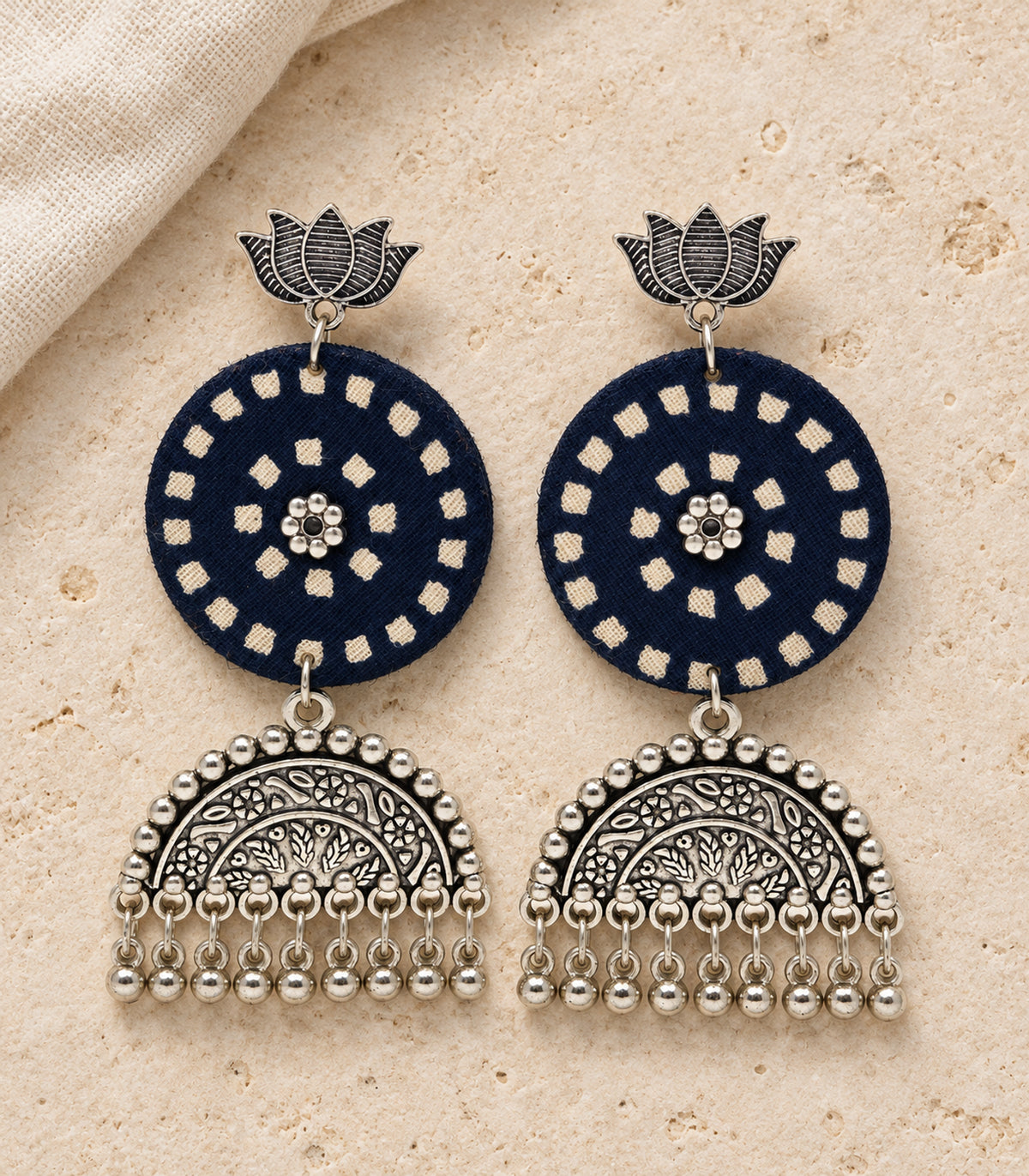 Navy and ivory lotus bell fringe fabric earrings — editorial flatlay view