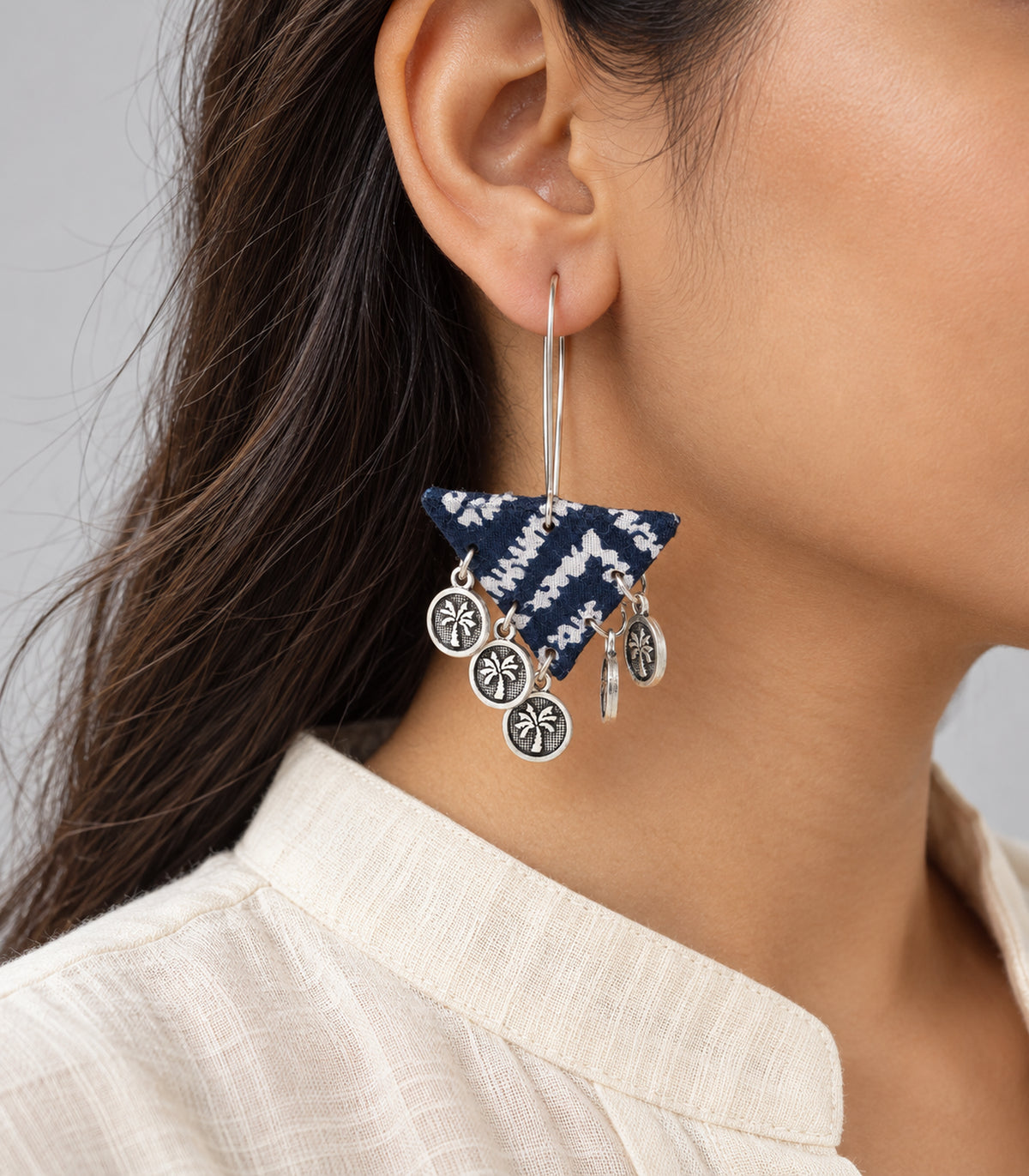 Closeup of navy and white fabric triangle earring with coin charms