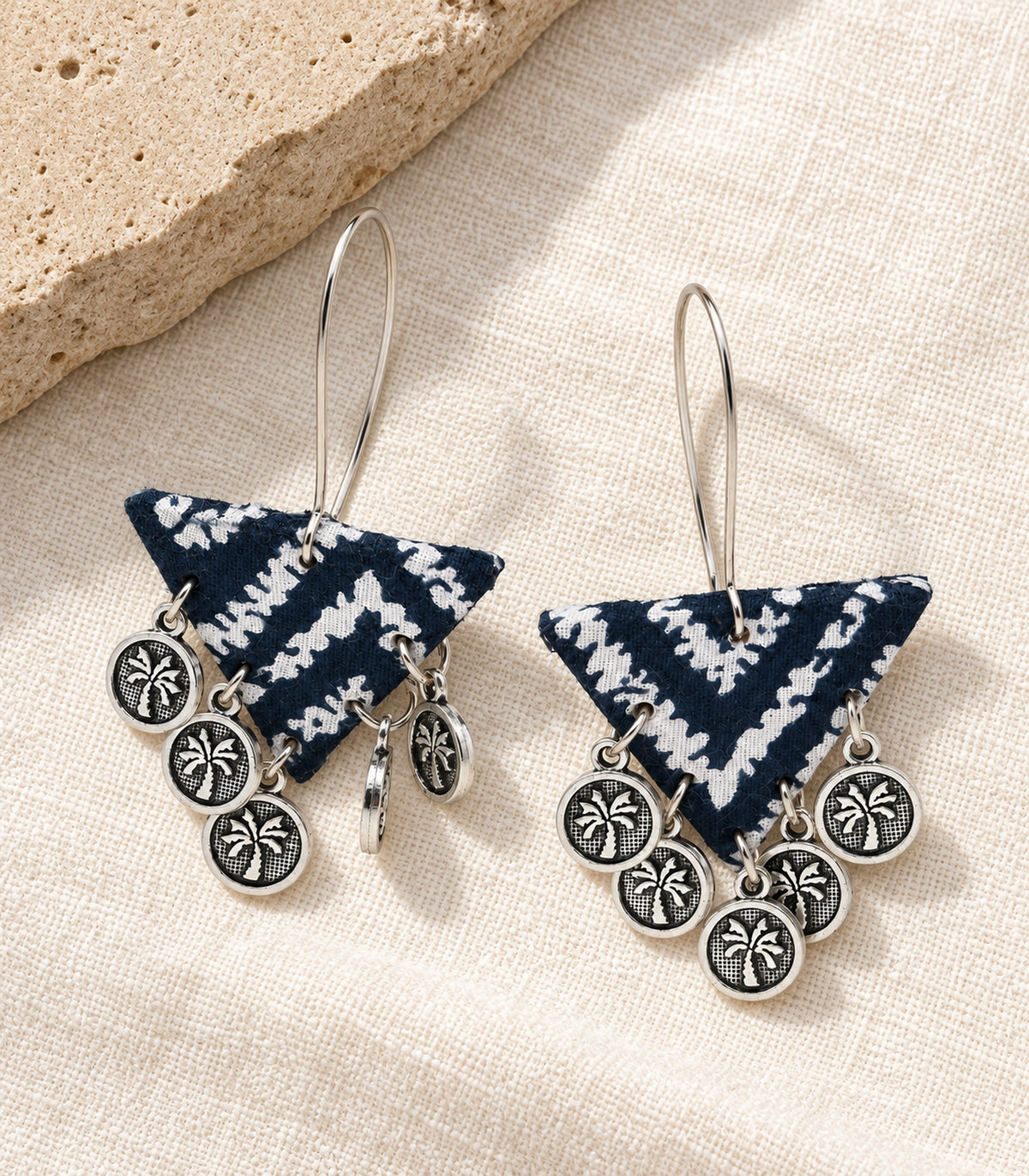 Complete pair of navy and white triangle coin earrings on ivory linen