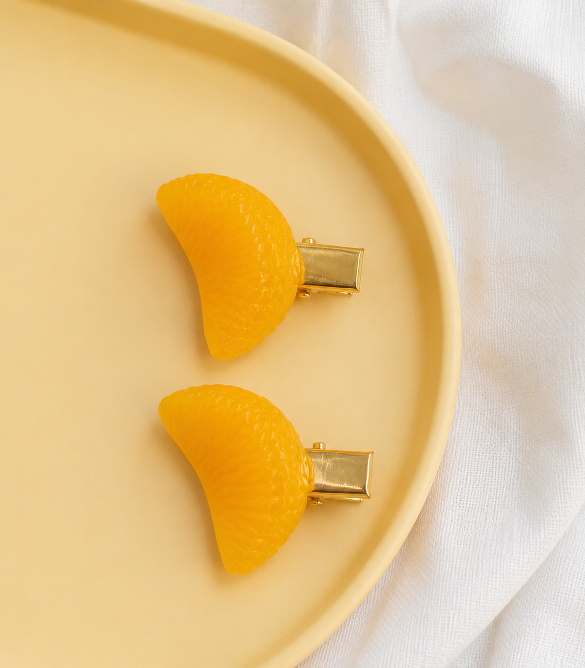 Orange Segment Barrette Pair editorial flat lay