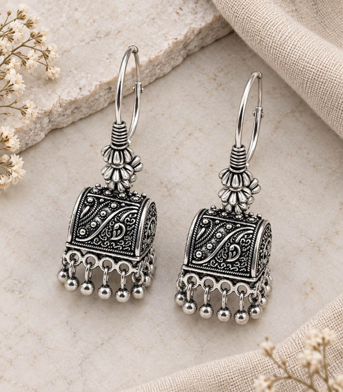 JIMIKI Oxidized Silver Paisley Cube Hoop Earrings - styled pair with textured fabric #color_oxidized-silver
