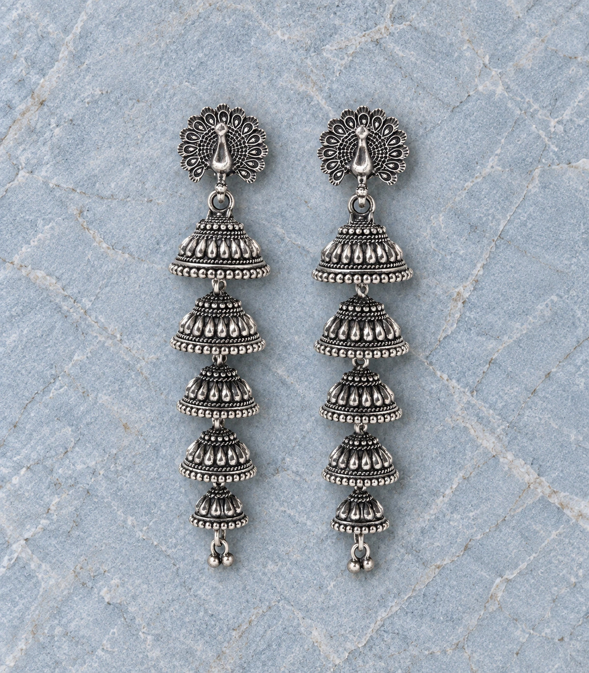 JIMIKI Peacock Five Tier Jhumka Earrings in Oxidized Silver - editorial flatlay #color_oxidized-silver