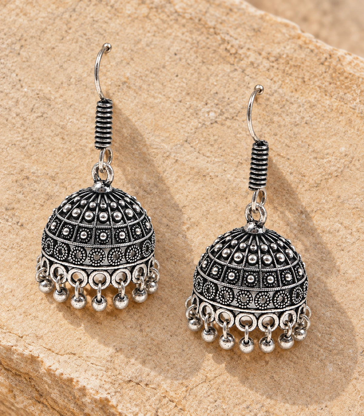 JIMIKI Oxidized Silver Rosette Grid Dome Jhumka Earrings - styled flatlay of the matching earrings #color_oxidized-silver