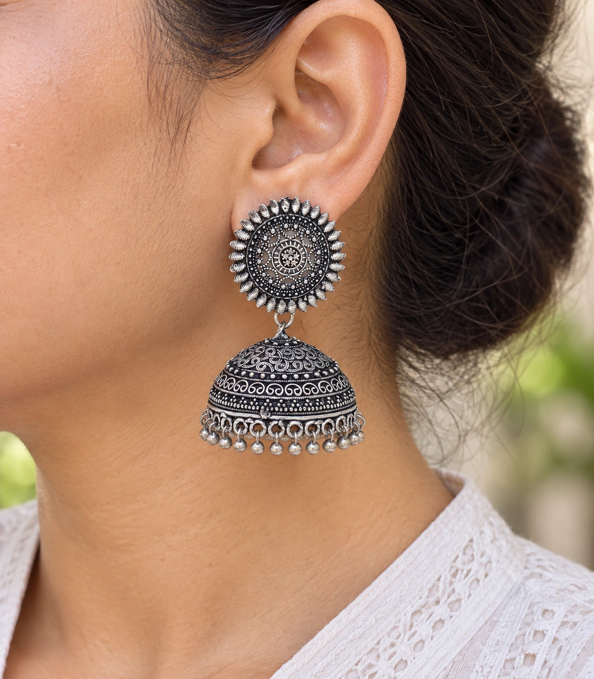 JIMIKI Oxidized Silver Sunburst Scroll Dome Jhumka Earrings - earring worn with a clear view of the design #color_oxidized-silver