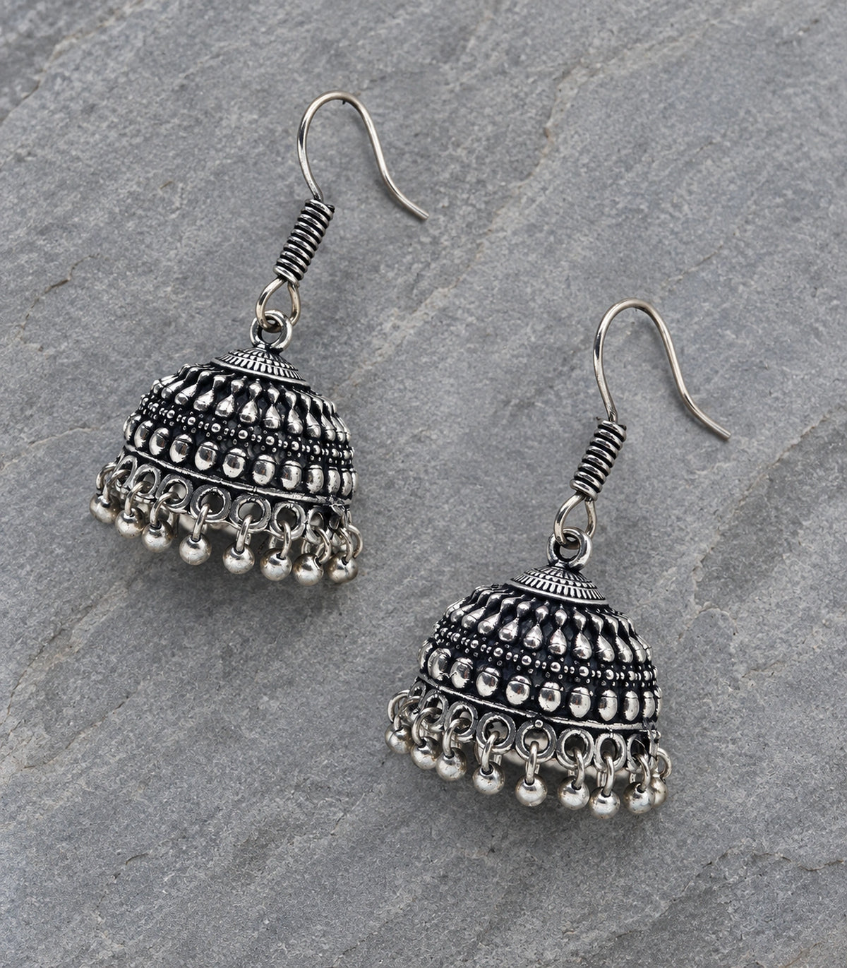 Oxidized silver-tone teardrop relief jhumka pair in an editorial flat lay #color_oxidized-silver