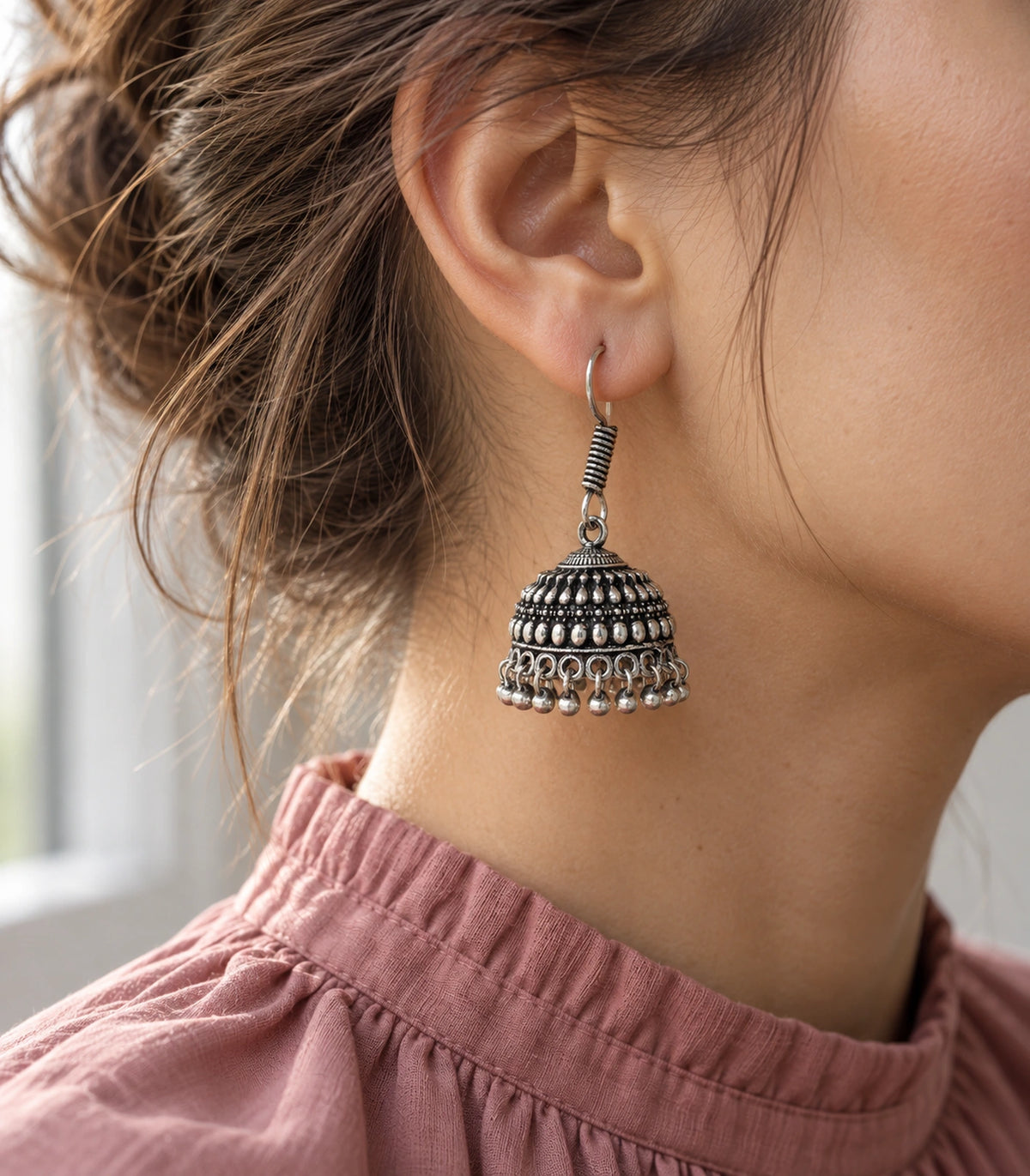 Editorial styling of oxidized silver-tone teardrop relief hook jhumka earrings #color_oxidized-silver