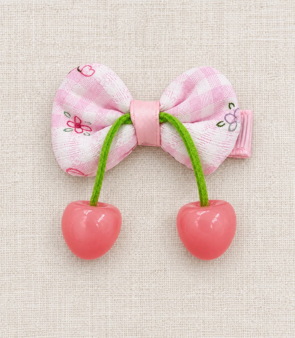 JIMIKI Pink Gingham Floral Bow Hair Clip with Cherry Charms in Pink, editorial flat lay